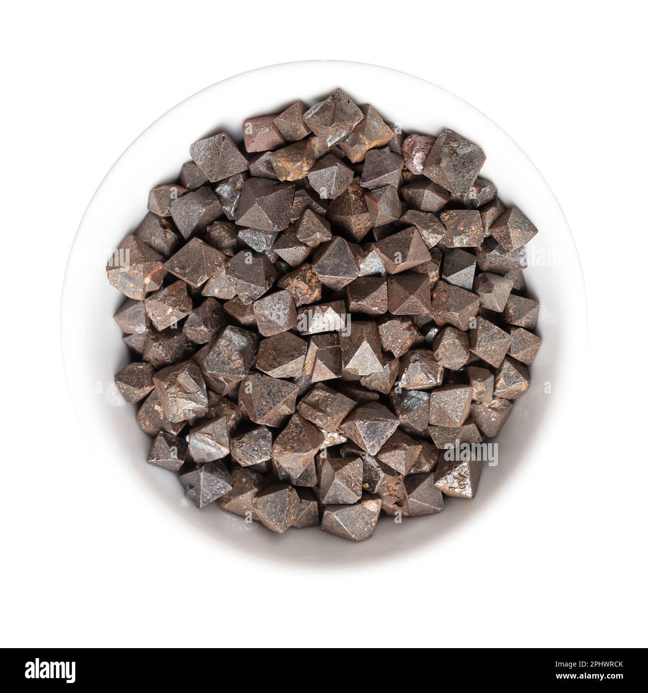Magnetite crystals in a white bowl. Iron(II,III) oxide, octahedral, double pyramid and Platonic solid shaped. Most magnetic of all occurring minerals. Stock Photo