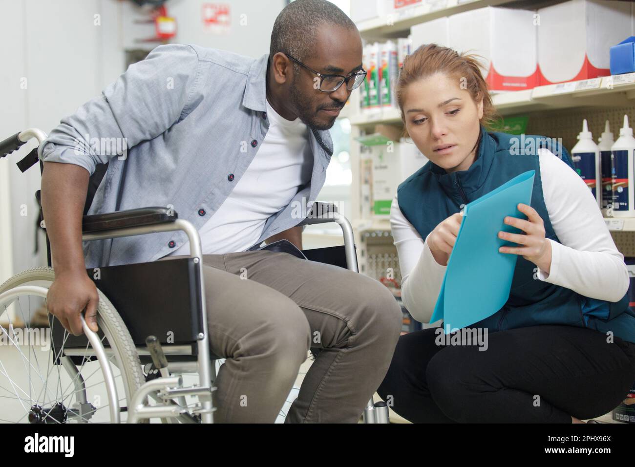 female shop assistant serving a customer in a wheelchair Stock Photo
