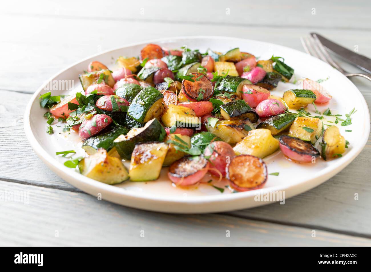 Pan fried caramelized vegetables with red radish, zucchini, parsley and olive oil Stock Photo