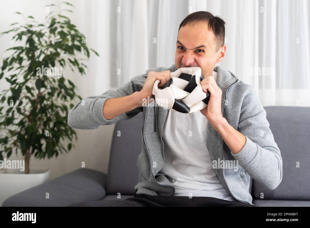 Young sad unhappy man fan in brown shirt hold remote controller spread