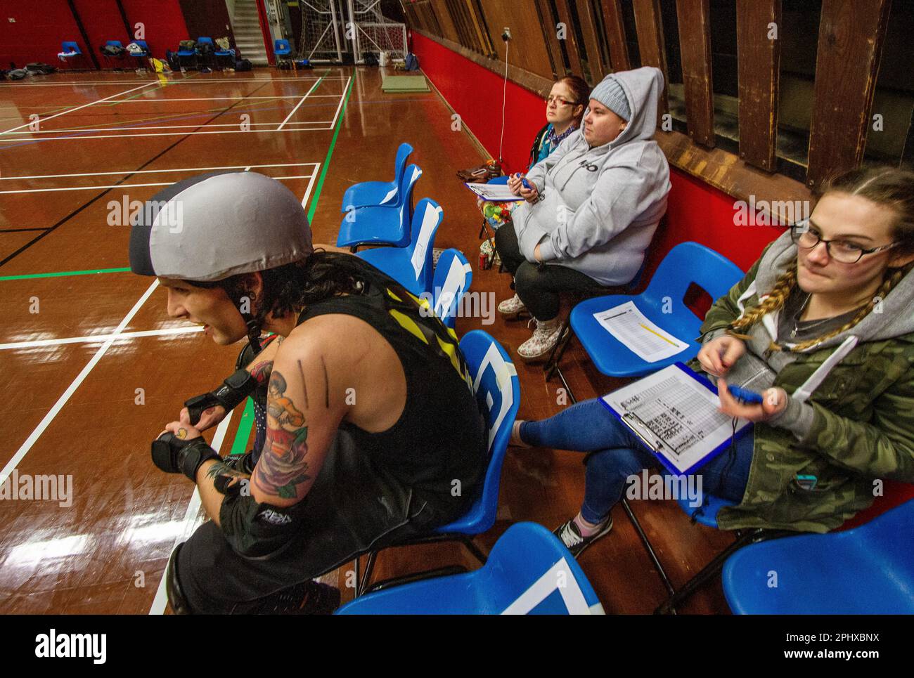 Non Skating Officials (NSOs) manage a roller derby penalty box where  penalised skaters have to wait off track to serve out there penalty Stock  Photo - Alamy