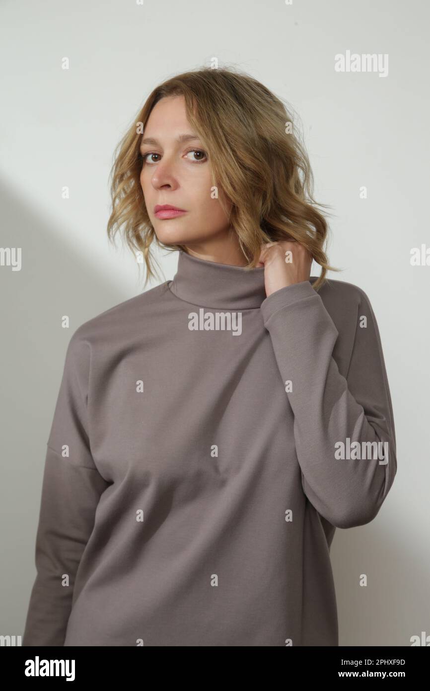 Serie of studio photos of young female model wearing classic grey brown basic turtleneck Stock Photo
