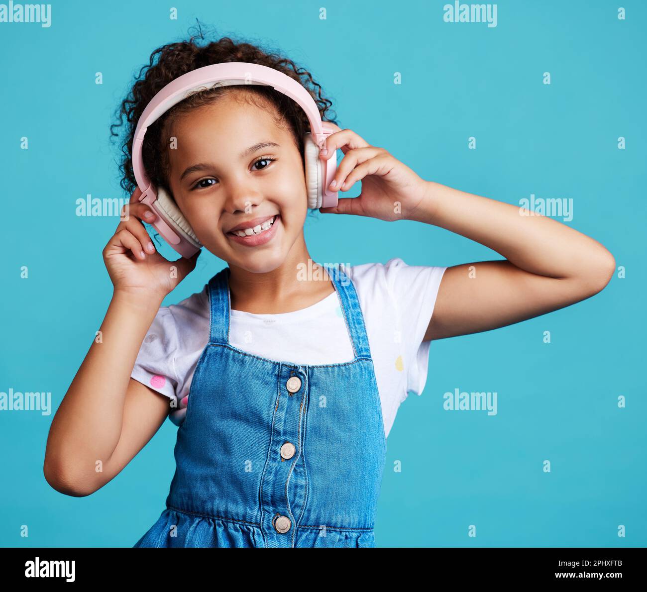 Music, portrait and girl child with headphones in studio for streaming, subscription and audio on blue background. Face, autism and autistic kid happy Stock Photo