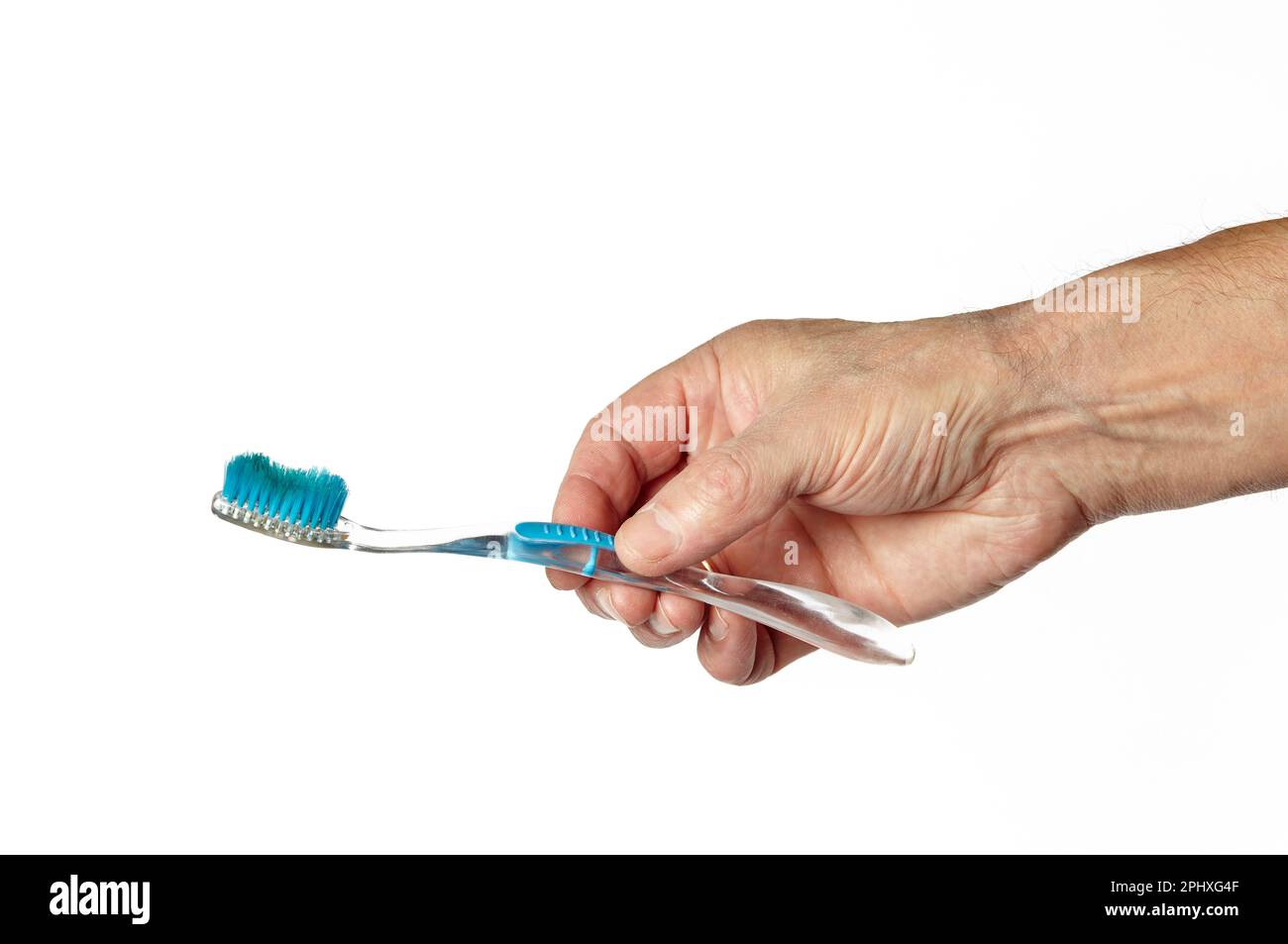 Men's hand holding a toothbrush without toothpaste isolated on white background. Hand holding toothbrush while going to clean teeth, closeup Stock Photo