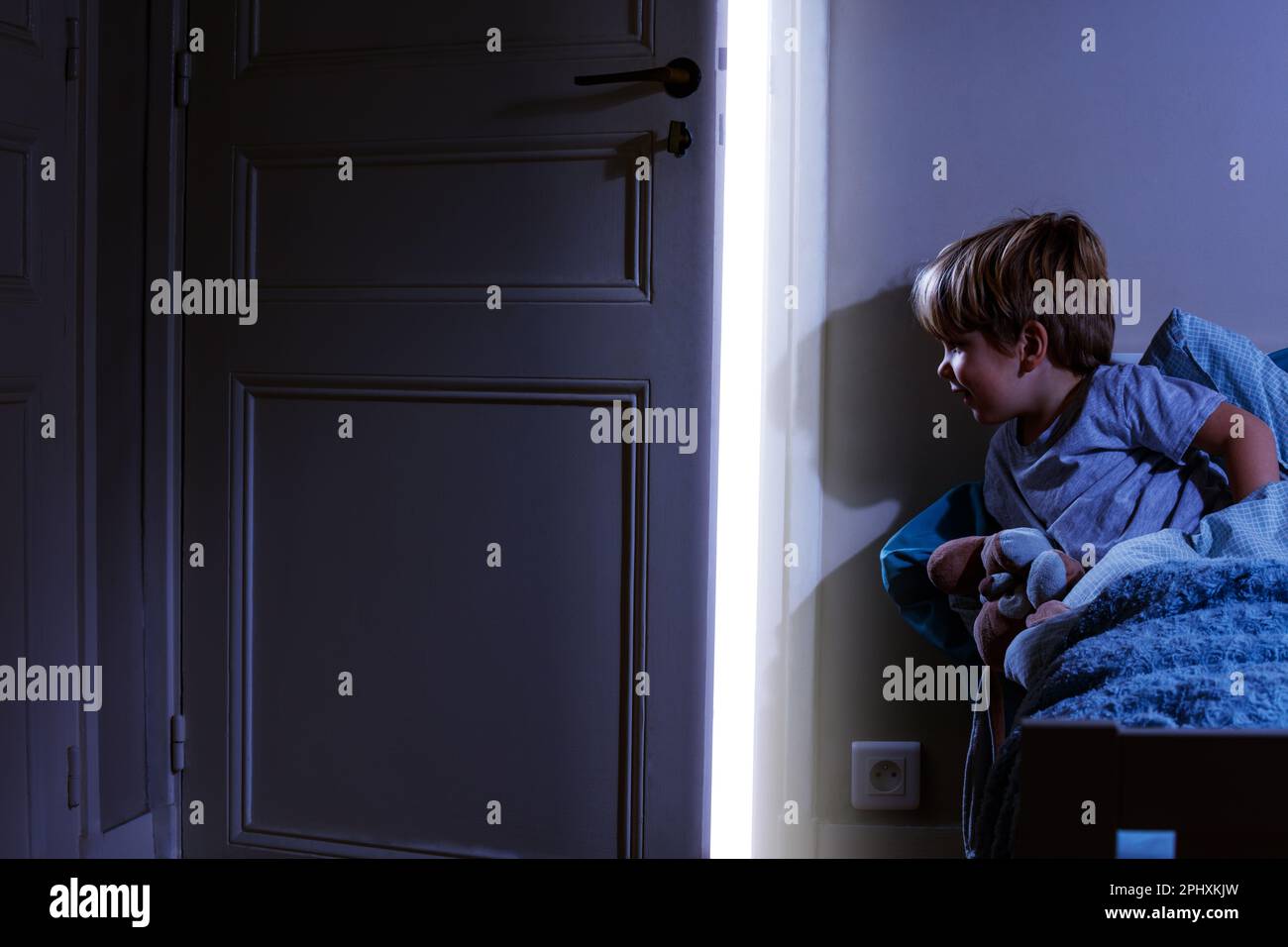 Child in bedroom look at light coming from the open door Stock Photo