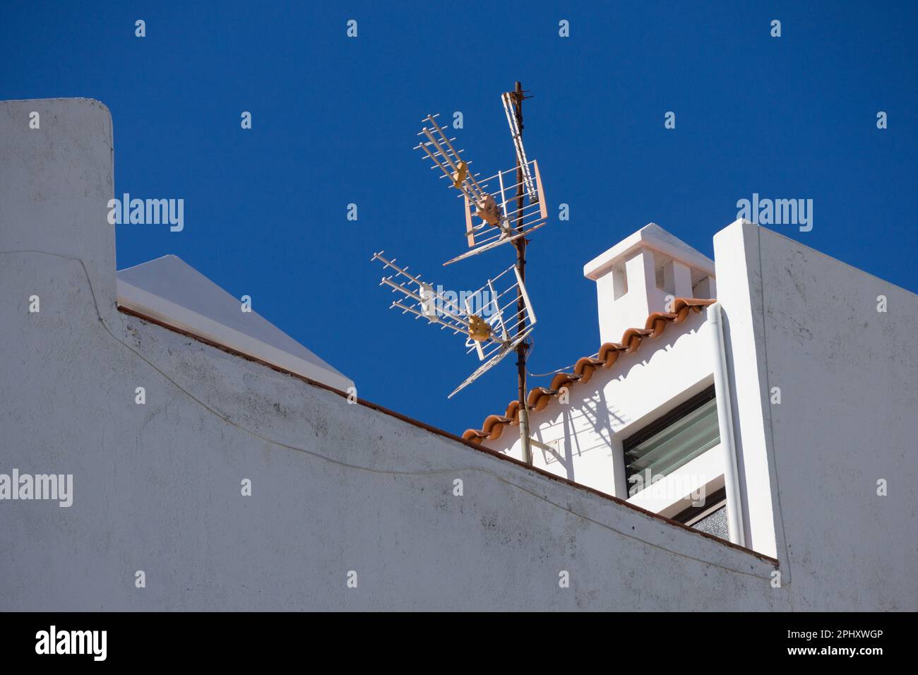 television antenna on a rooftop in front of a blue sky Stock Photo