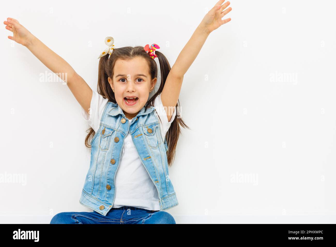 happy little girl with hands raised on white background Stock Photo - Alamy