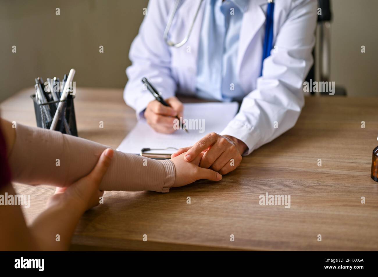 Close-up image of a professional female orthopedic doctor holding her patient hand to comfort and reassure during the meeting. Stock Photo