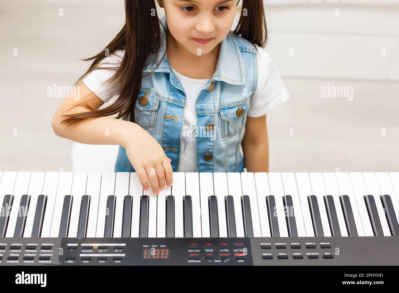 Cute little girl plays on piano, synthesizer. Training. Education. School.  Aesthetic training. Elementary classroom Stock Photo - Alamy