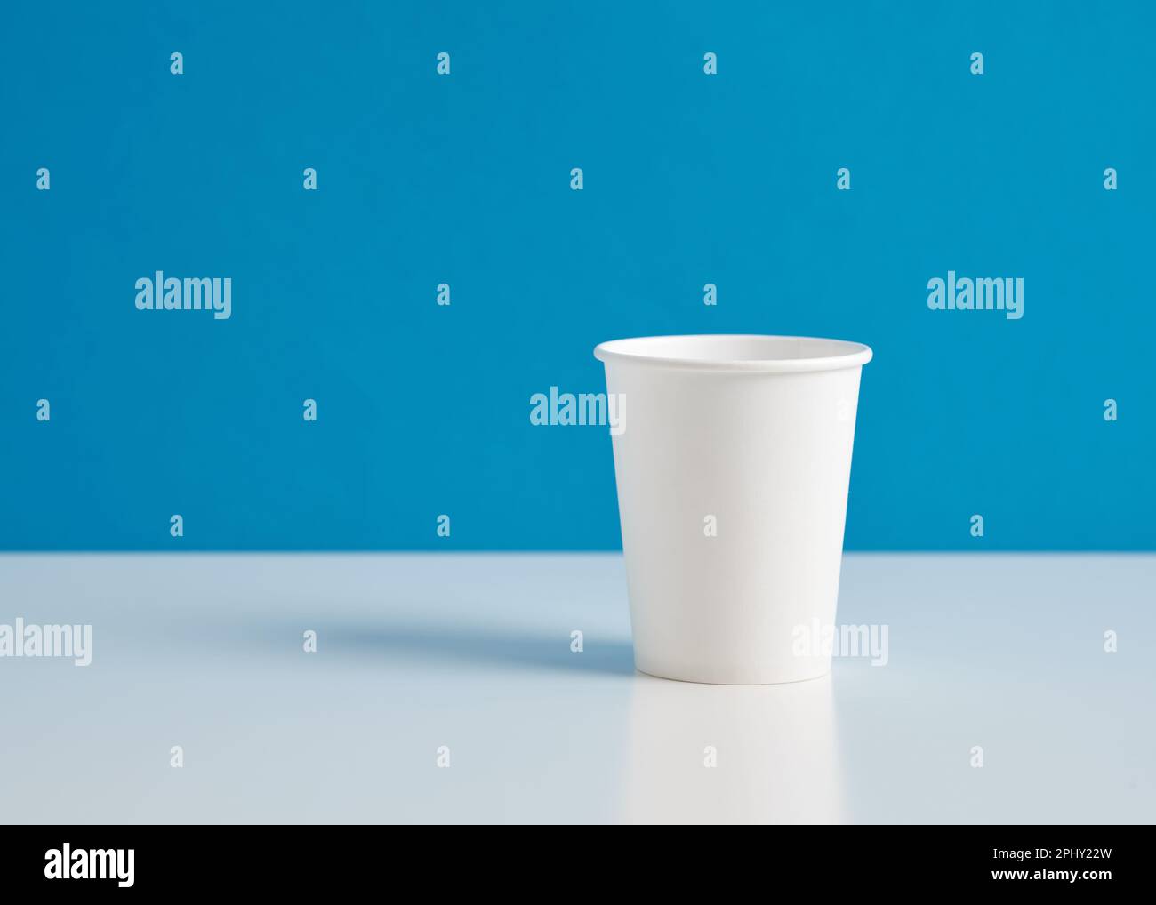 White paper cup on blue background. Stock Photo