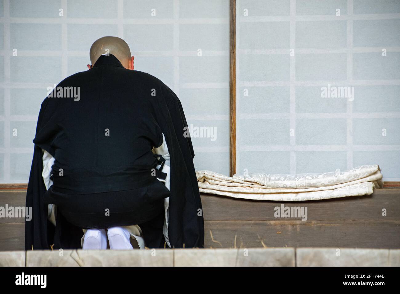 Rear view of a japanese monk wearing black cloths and praying, Japan