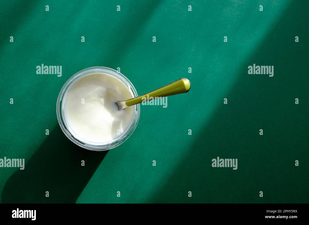 natural yoghurt in plastic container on green background Stock Photo