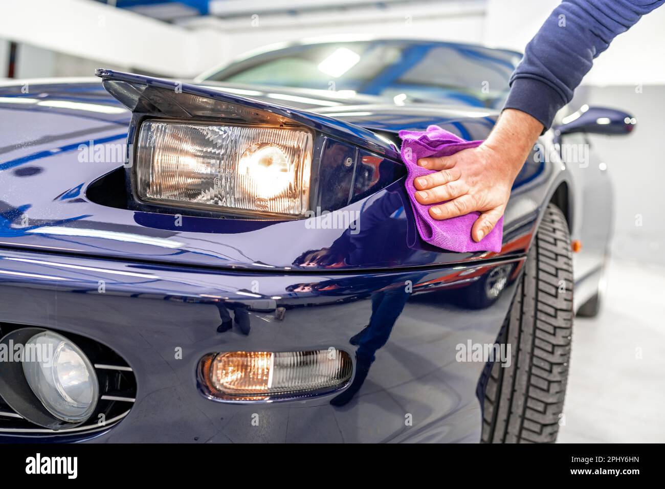 detailing and polishing the body of a luxury sports car using a micro fiber. flip up car light Stock Photo