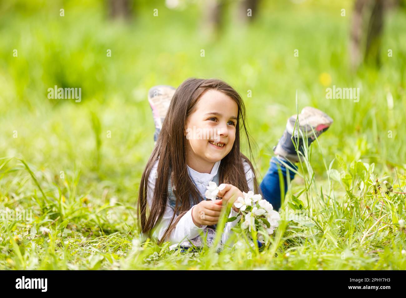 Portrait of a smiling little girl lying on green grass Stock Photo - Alamy