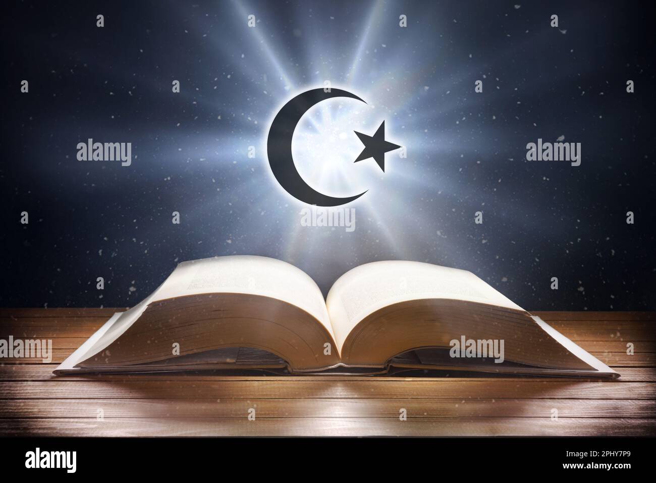 Open book on wooden table and islamic symbol with beam of light with dark background. Front view. Stock Photo
