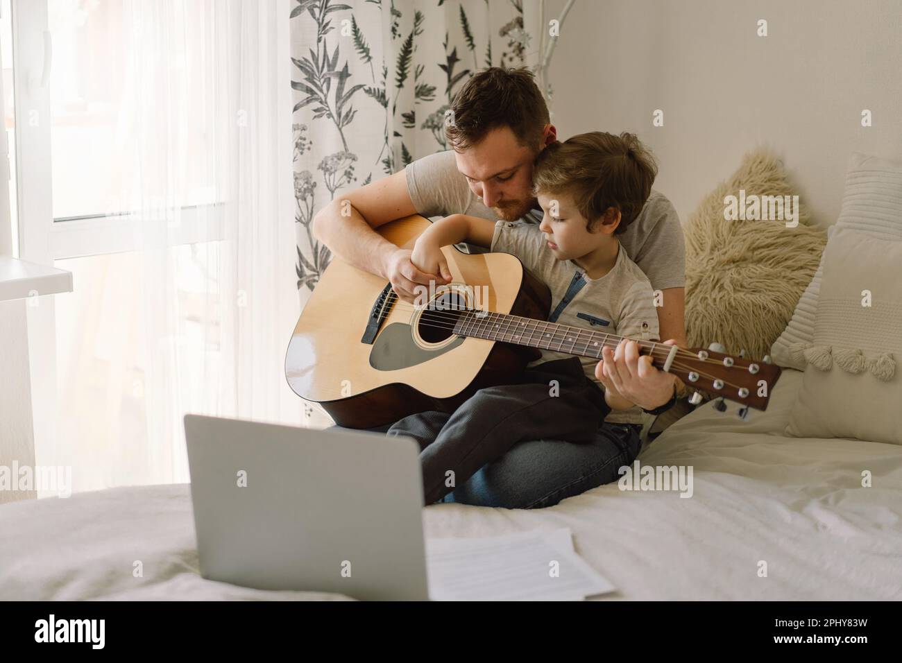 Father and son learn to play the acoustic guitar in an online lesson. Happy  Father's day Stock Photo - Alamy