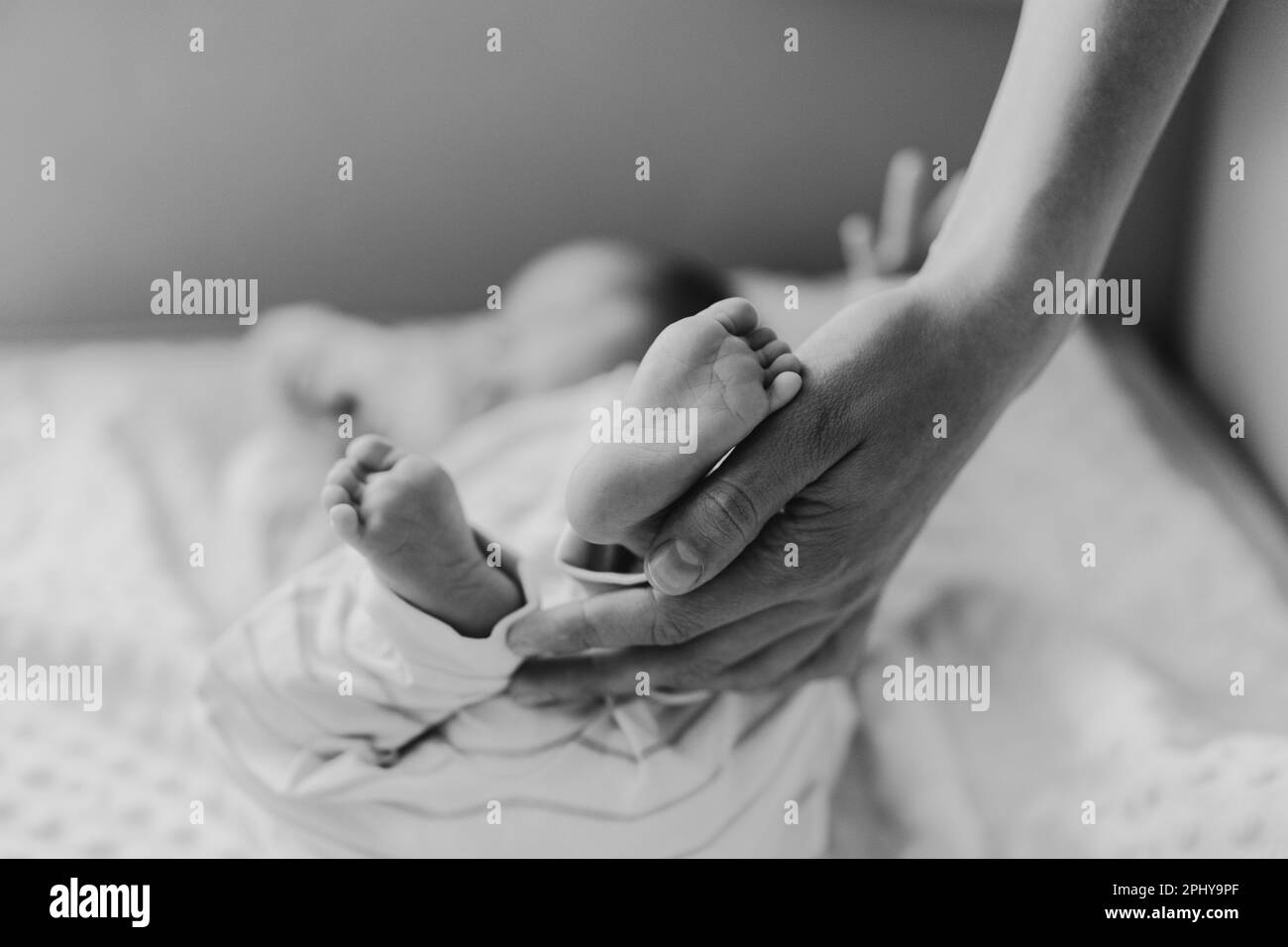 Mother playing with newborn baby son at home. Happy infant and mom. Stock Photo