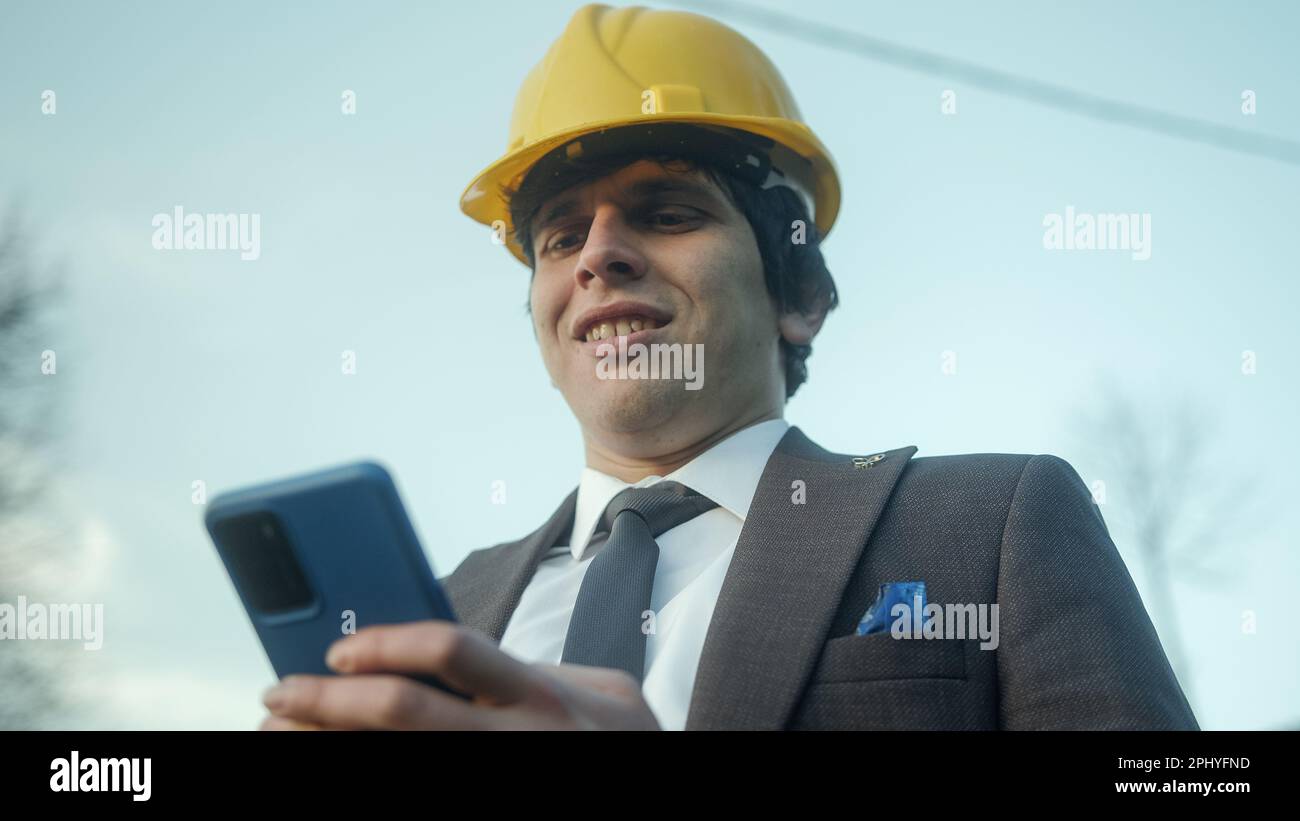 Modern Business and Shopping: A Young Entrepreneur or Civil Engineer Using a Smartphone for Online Purchases Stock Photo