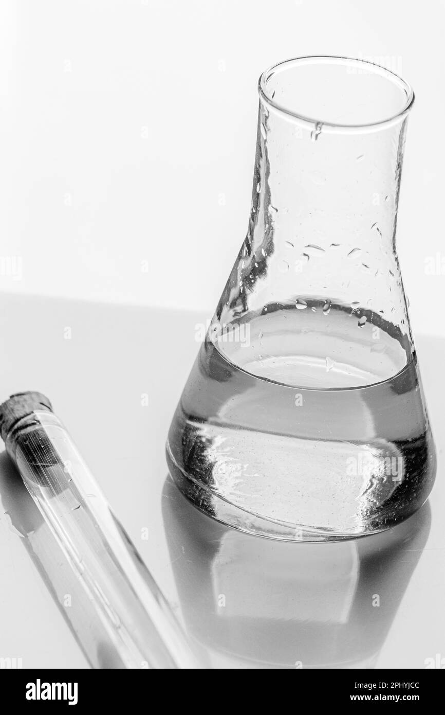 Glass medical test tube and liquid flask stand on mirror table