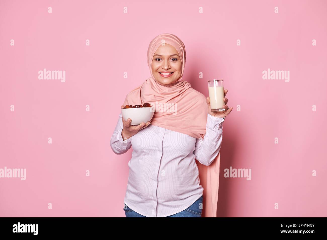 Pregnancy and calcium. Muslim pregnant woman in pink hijab, holding