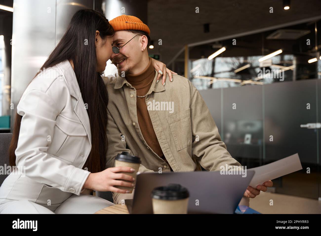 Romantic female office worker hugging her coworker at desk Stock Photo