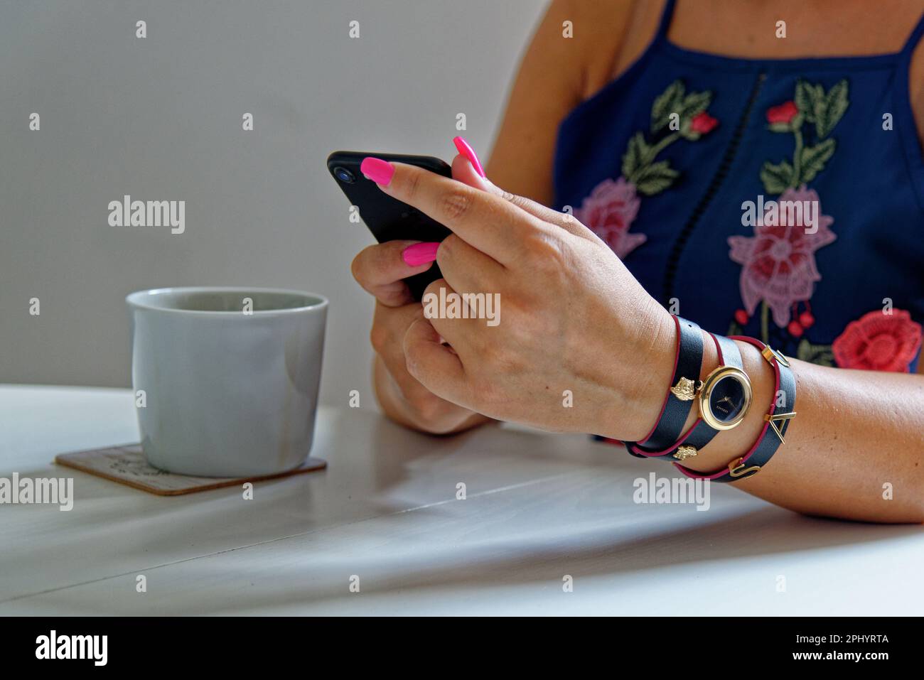 Woman browsing phone and having a cup of coffee wearing fashion jewelery - London, United Kingdom, 1st of June 2019 Stock Photo