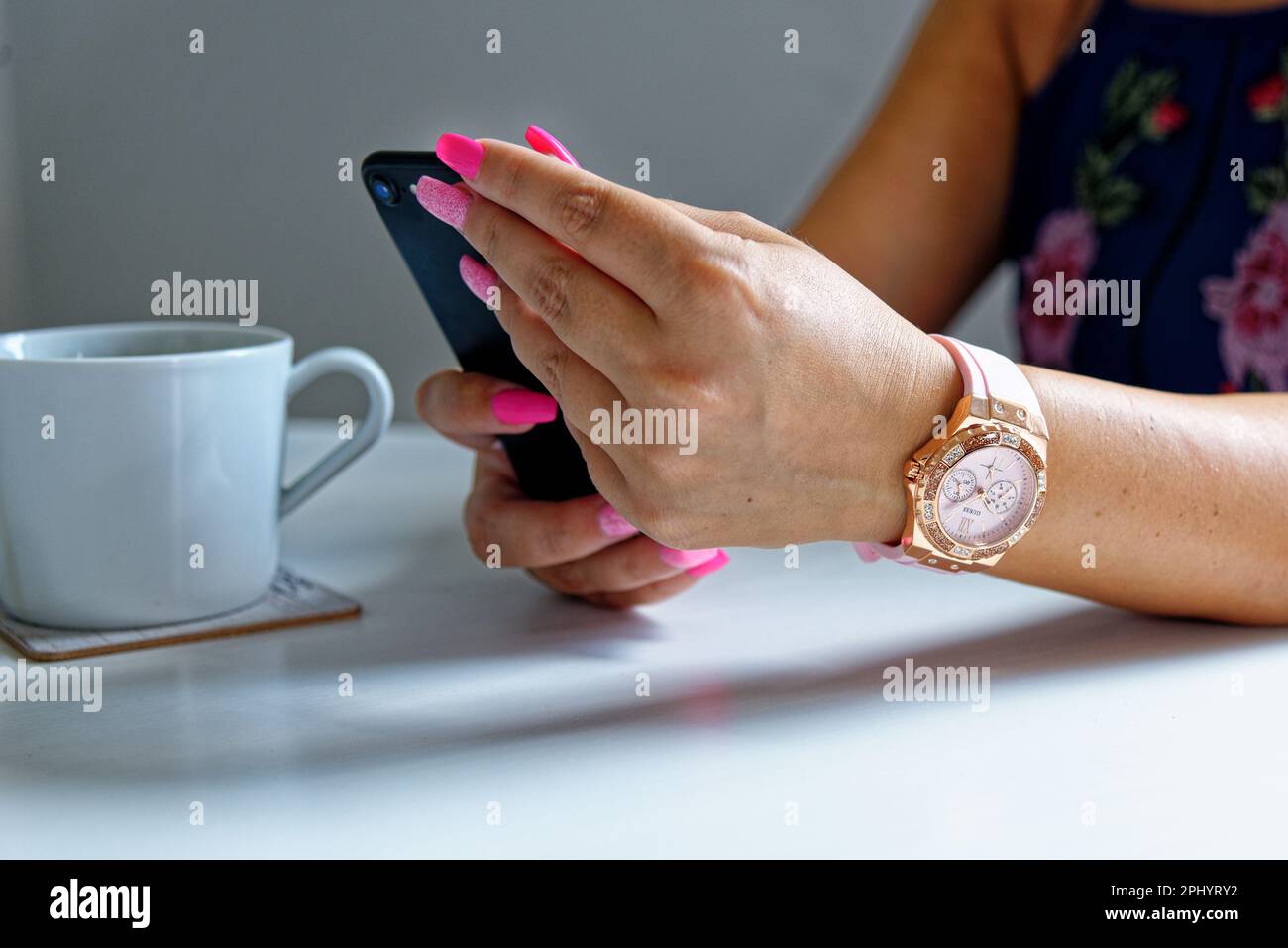 Woman browsing phone and having a cup of coffee wearing fashion jewelery - London, United Kingdom, 1st of June 2019 Stock Photo