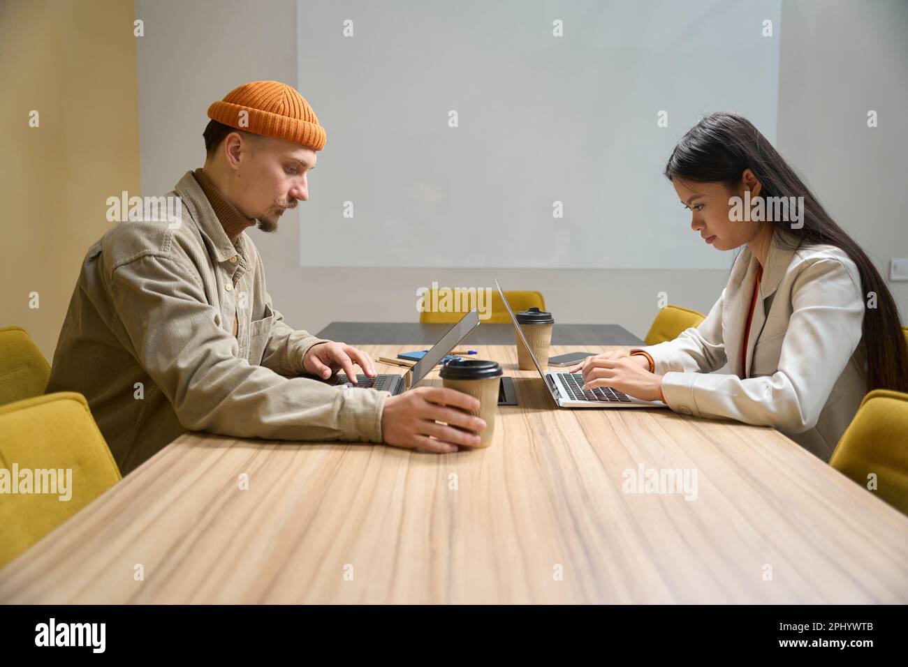 Office workers working on laptops in meeting room Stock Photo