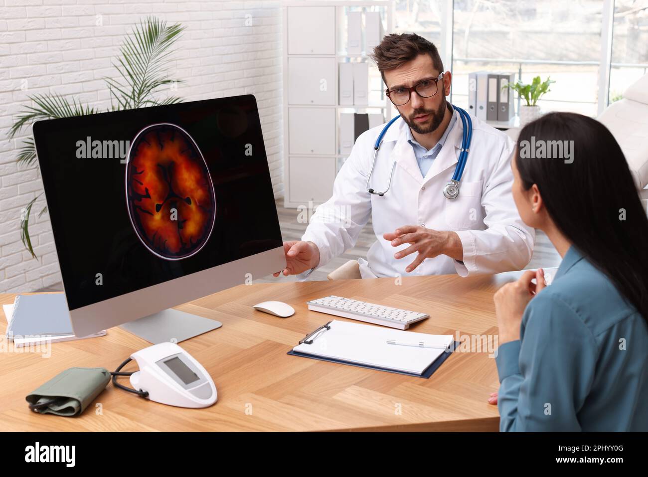 Neurologist showing brain scan to young woman in clinic Stock Photo - Alamy