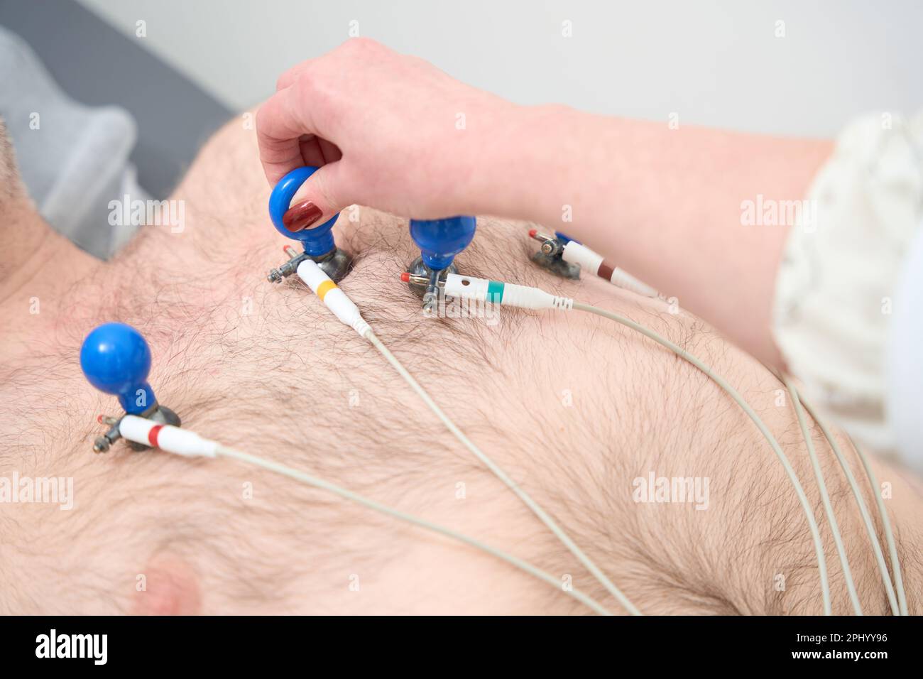 Doctor sticking vacuum electrodes on young male patient chest in