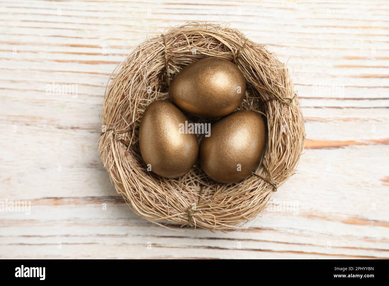 Golden eggs in nest on white wooden table, top view Stock Photo - Alamy