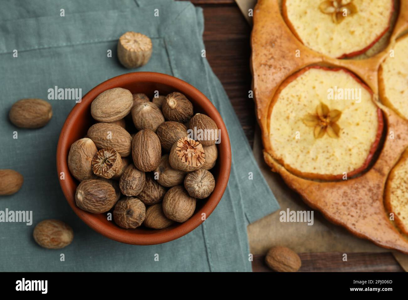 Nutmeg seeds and tasty apple pie on wooden table, flat lay Stock Photo