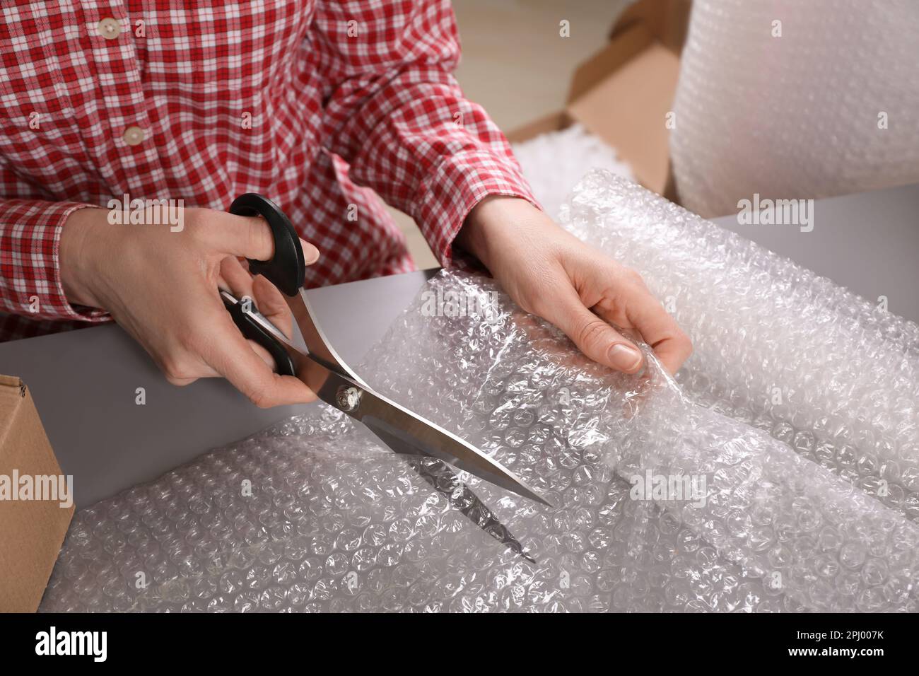 Woman cutting bubble wrap at table in warehouse, closeup Stock Photo Alamy