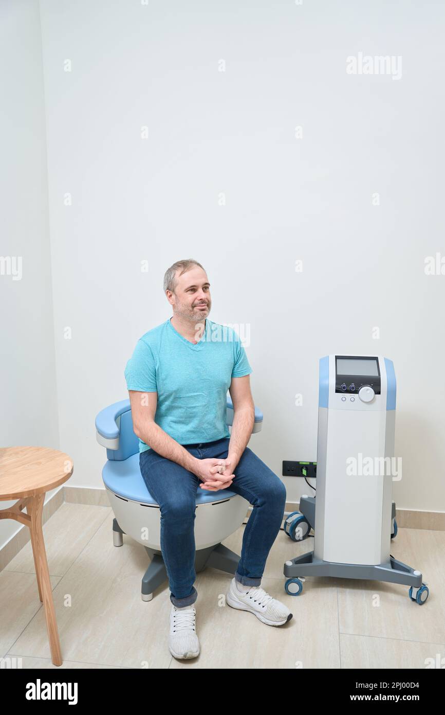 Happy man sitting waiting for doctor while sitting on exam room Stock Photo