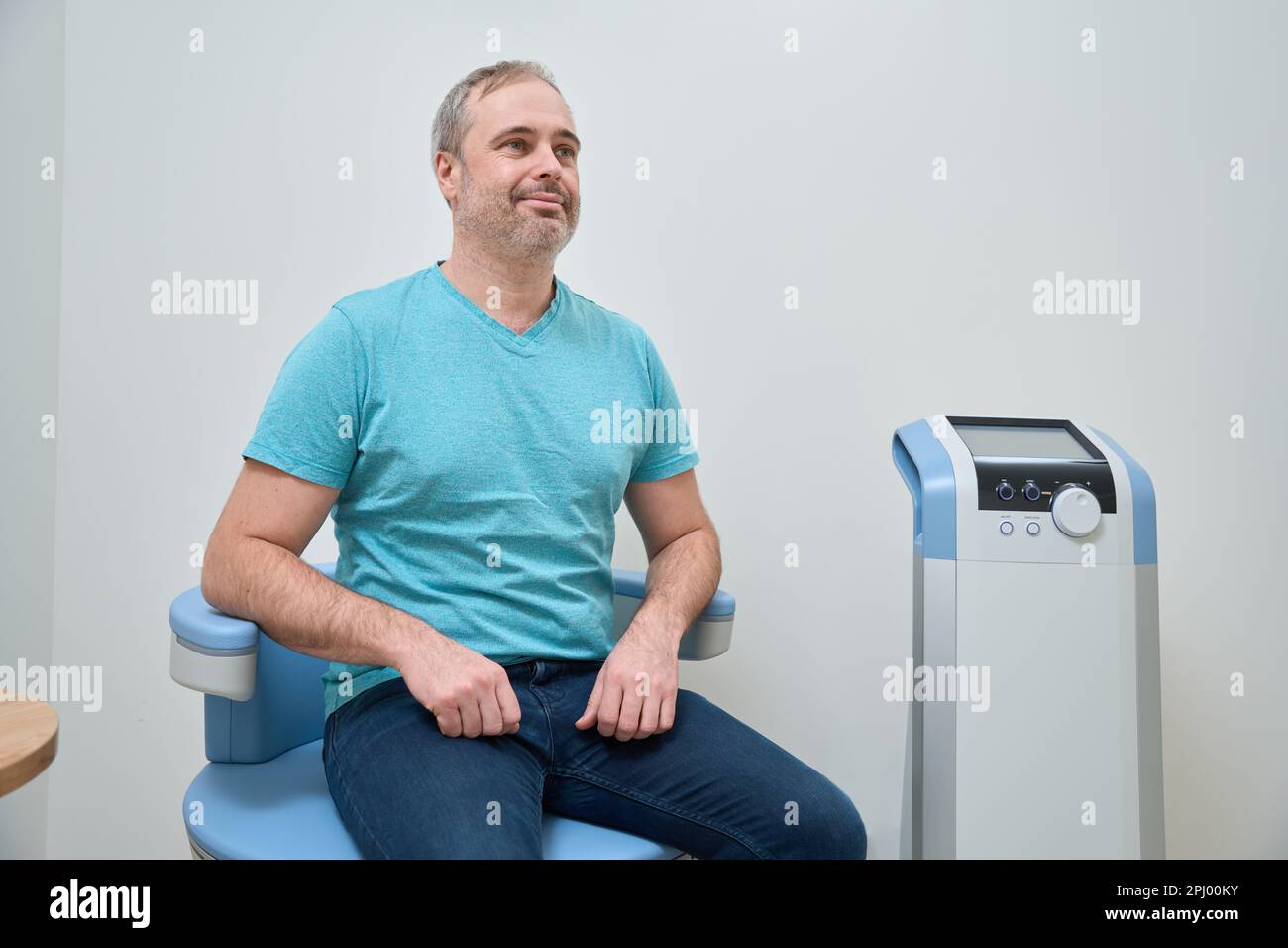 Happy man sitting waiting for RF lifting procedure Stock Photo