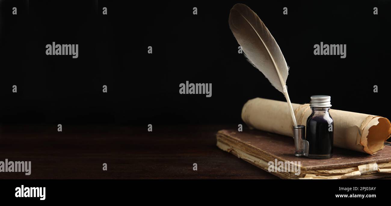 Quill, bottle of ink, old book and parchment scroll on wooden table, space for text. Banner