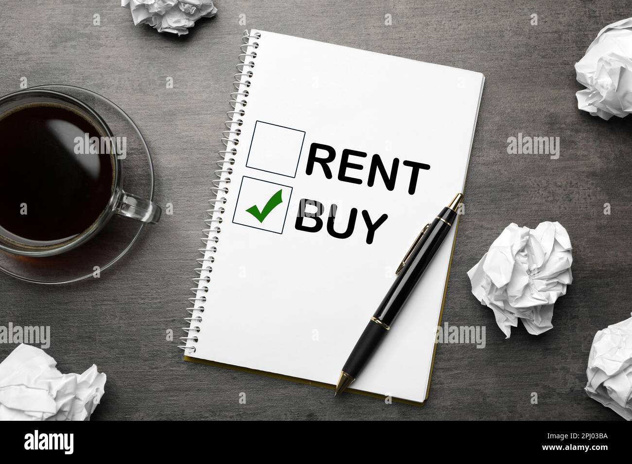 Buy or rent - choice concept. Flat lay composition with crumpled paper balls and notebook on grey table Stock Photo