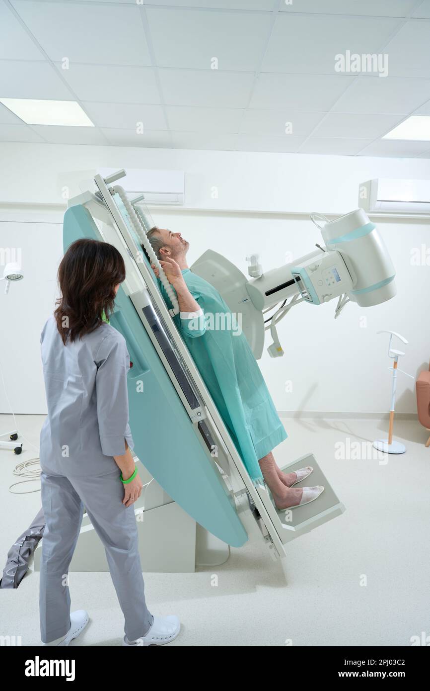 Medical technician standing near XRay machine while helping for man