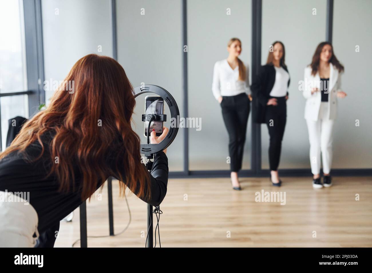 Backstage of photoshoot. Group of adult women that in formal clothes is indoors in the office together Stock Photo