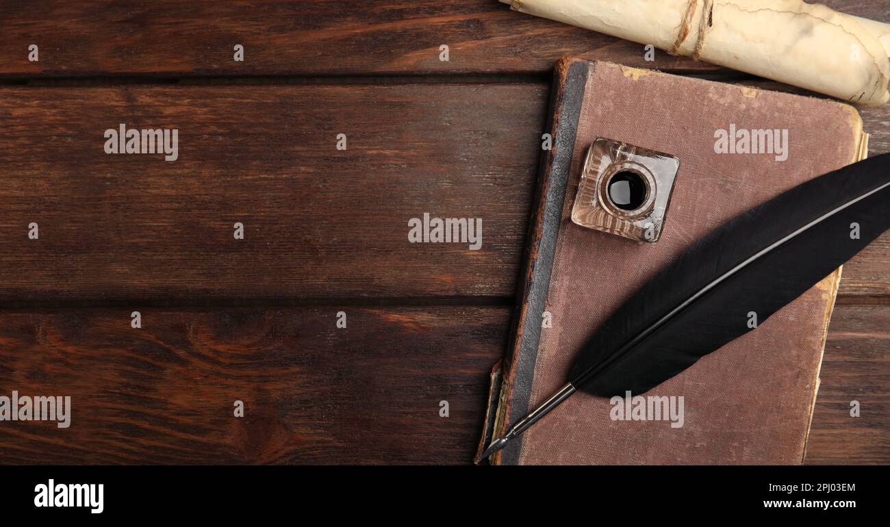 Quill, inkwell, old book and parchment scroll on wooden table, flat lay ...