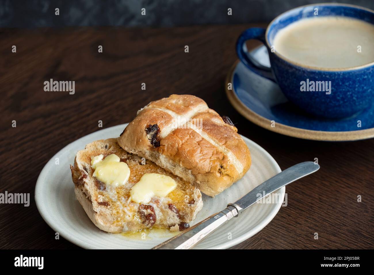 A Easter Hot Cross Bun, toasted and served with butter which is melting on the warm bun. Traditionally served on Good Friday in the UK Stock Photo