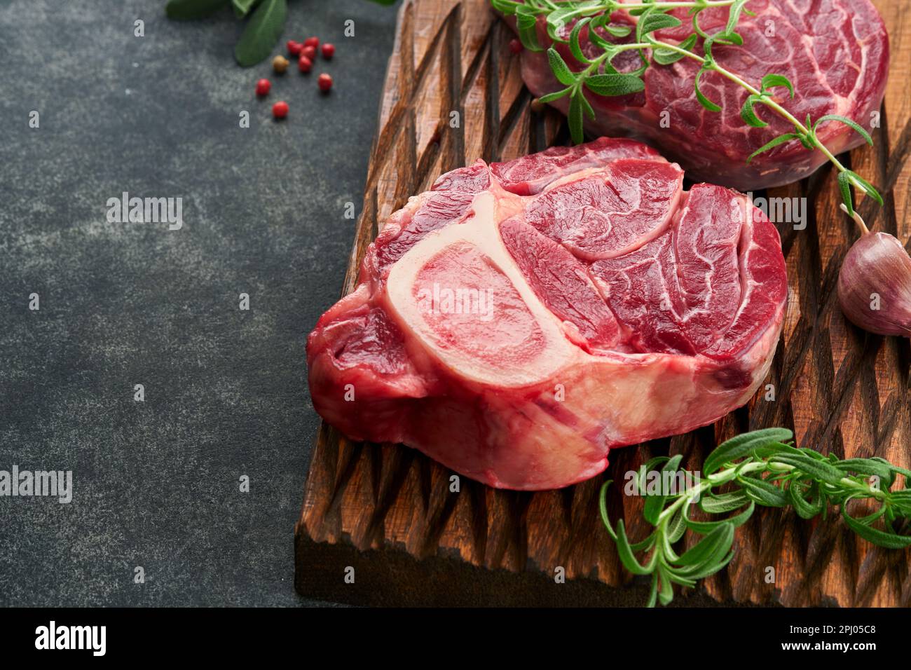 Osso Buco raw steak meat. Barbecue meat. Raw fresh cross cut veal shank and seasonings pepper, rosemary, thyme and salt on old wooden rustic backgroun Stock Photo