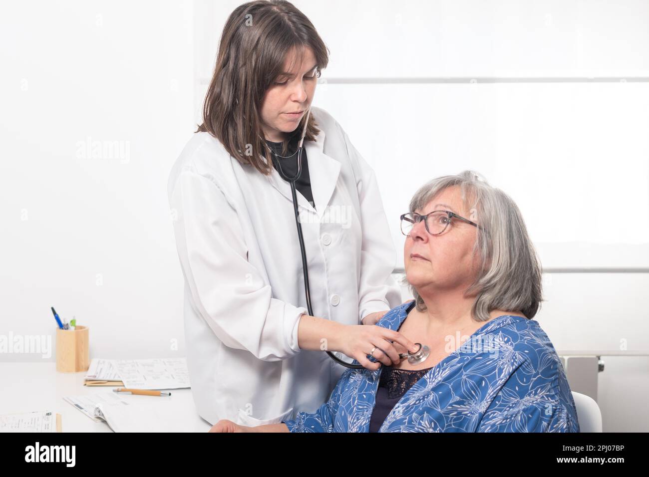 Young female doctor auscultating a patient with her stethoscope against ...