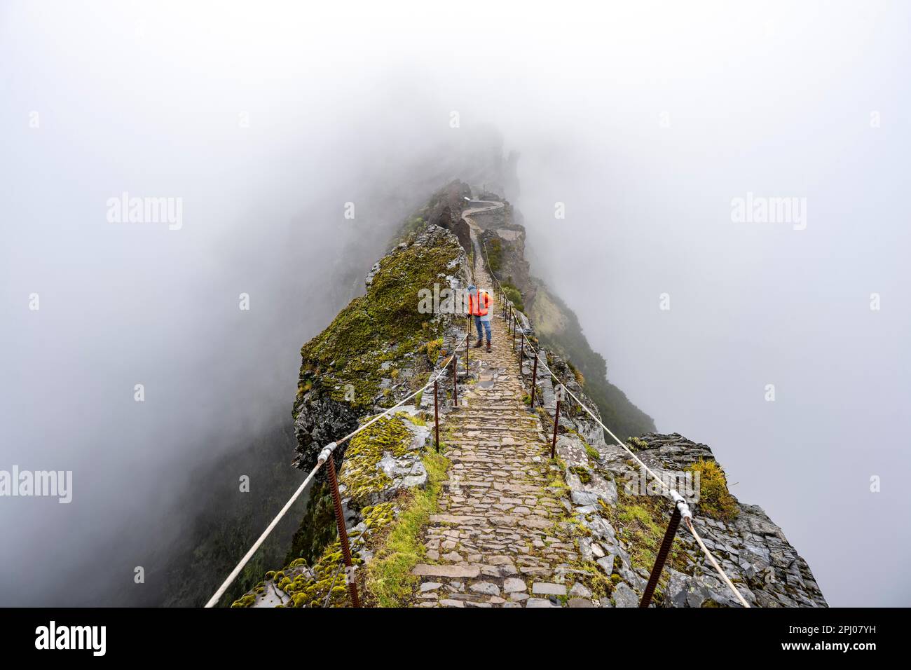 Hikers in the mist, Pico Arieiro to Pico Ruivo hike, narrow exposed trail on rocky cliff, Central Mountains of Madeira, Madeira, Portugal Stock Photo