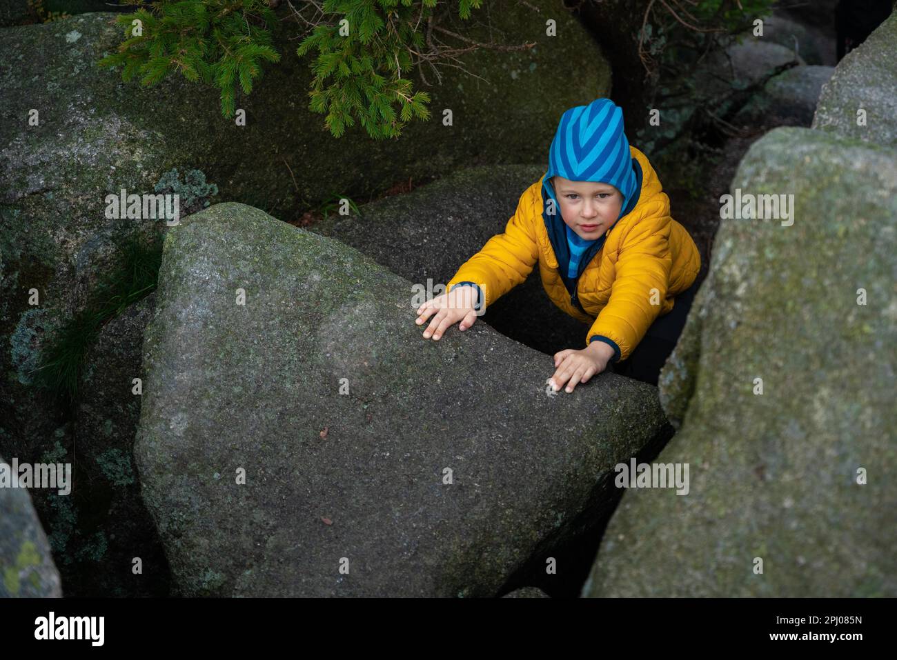 Happy child standing between large boulders on the hiking trail. Polish mountains Stock Photo