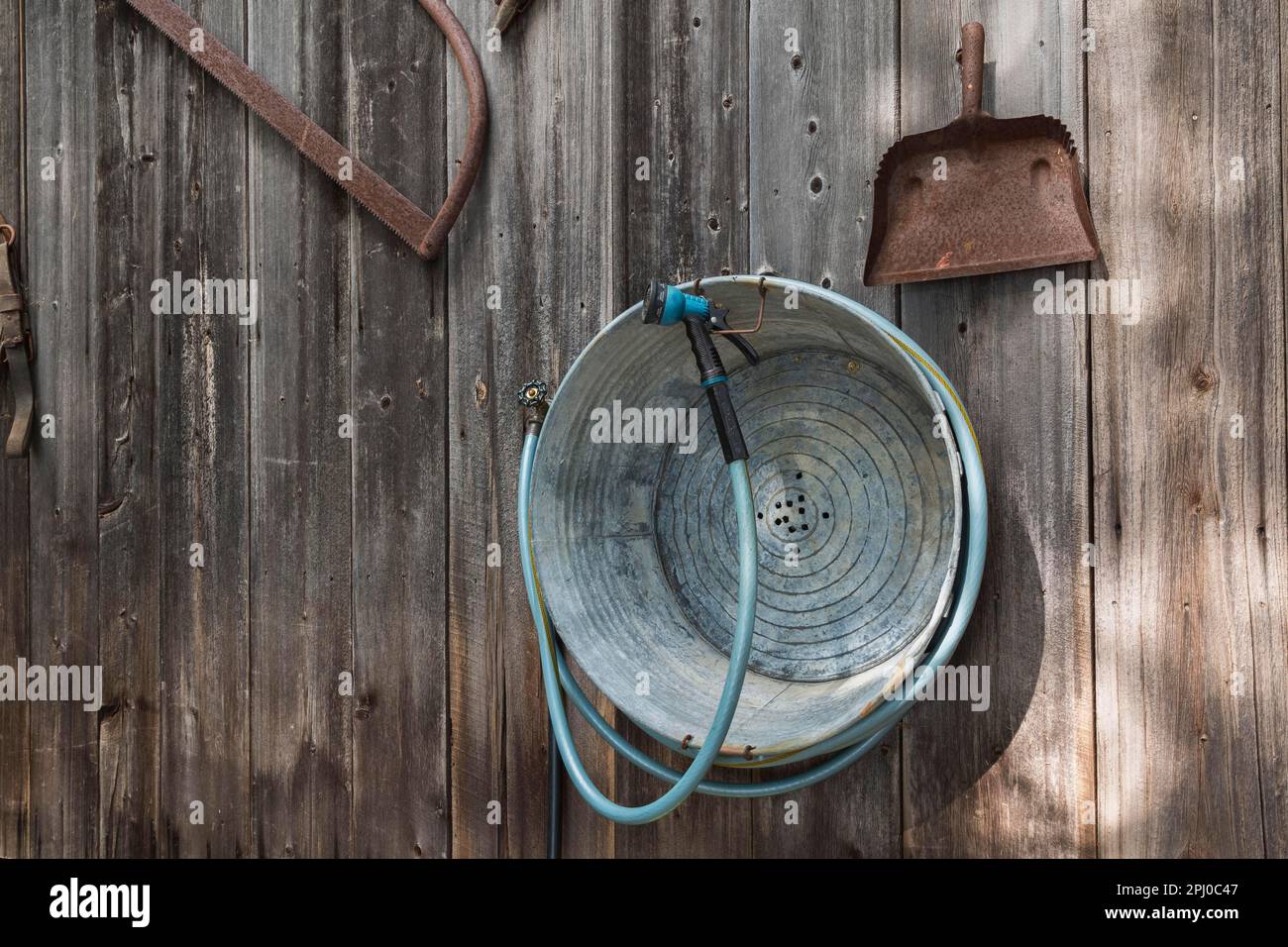 Old galvanized utility tub, rusted dustpan, manual saw displayed on