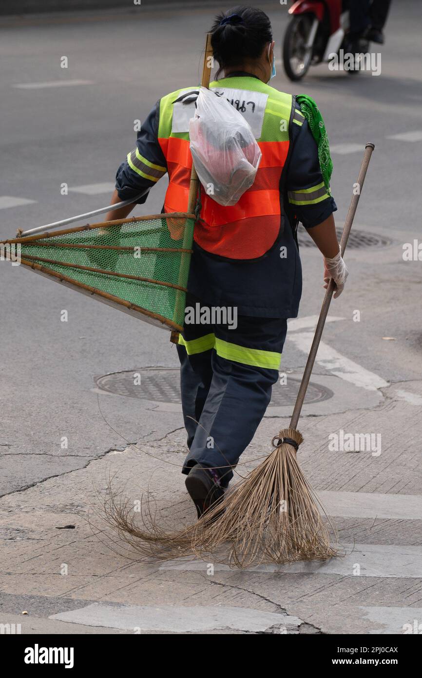 Street cleaner with his broom and waste collector in hand, walks the