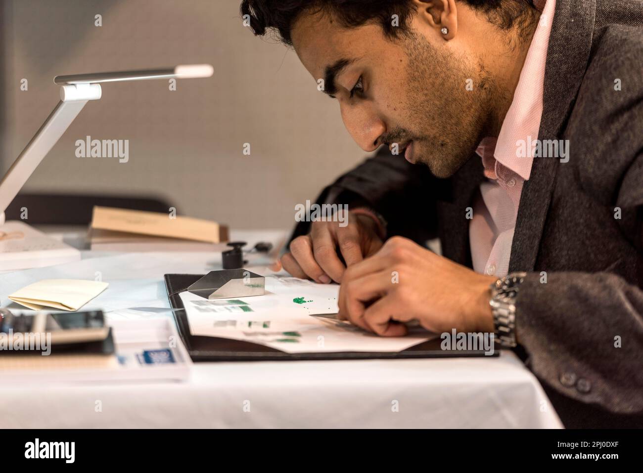 Man sorts small cut slivers from emerald, TGL Group stand, Inhorgenta, trade fair for jewellery watches gemstones, luxury, Munich, Upper Bavaria Stock Photo