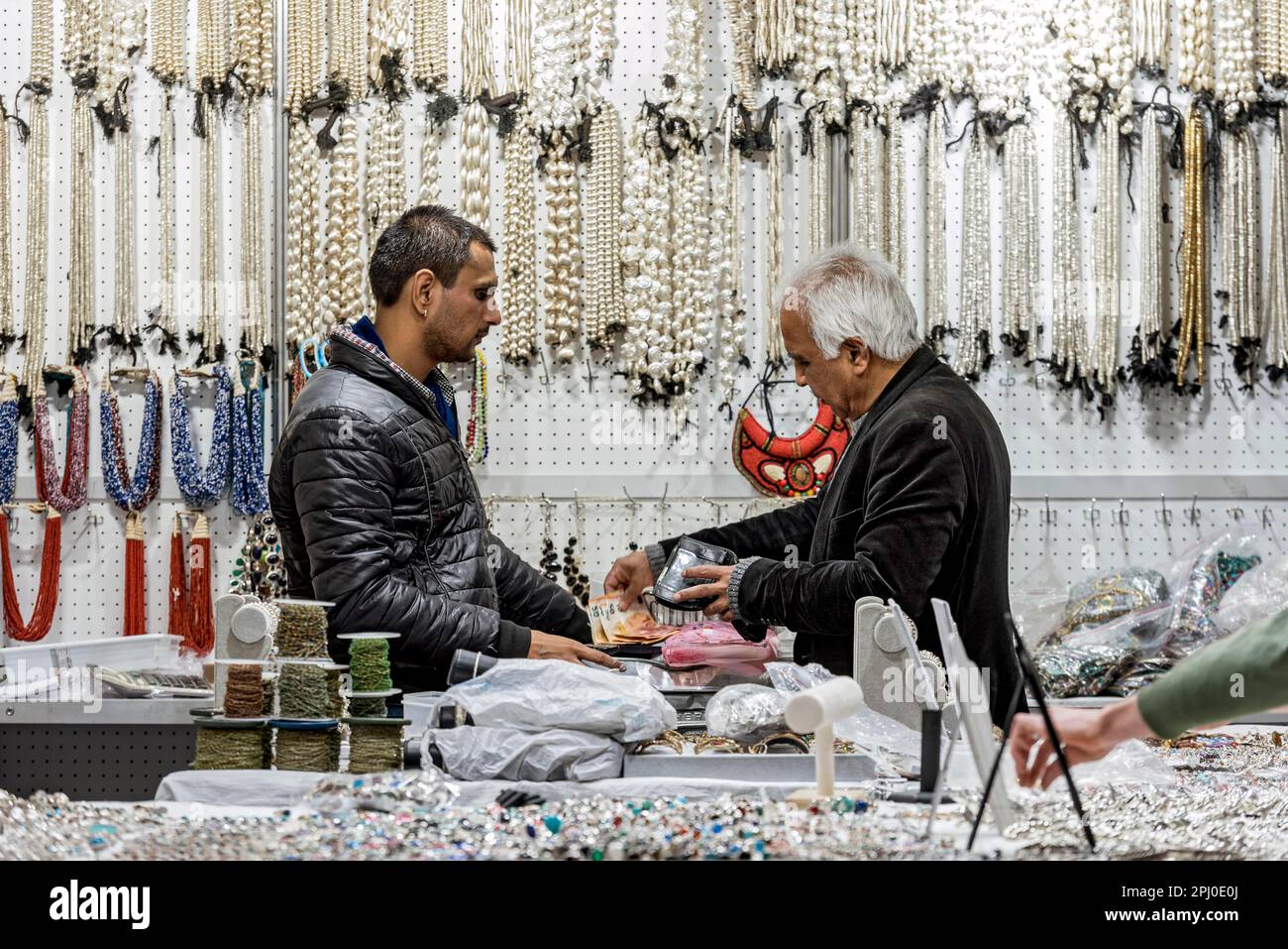 Men paying in cash at trade fair stand for minerals, gemstones, pearl necklaces, stone necklaces, womans hand grabs goods unnoticed, Inhorgenta Stock Photo