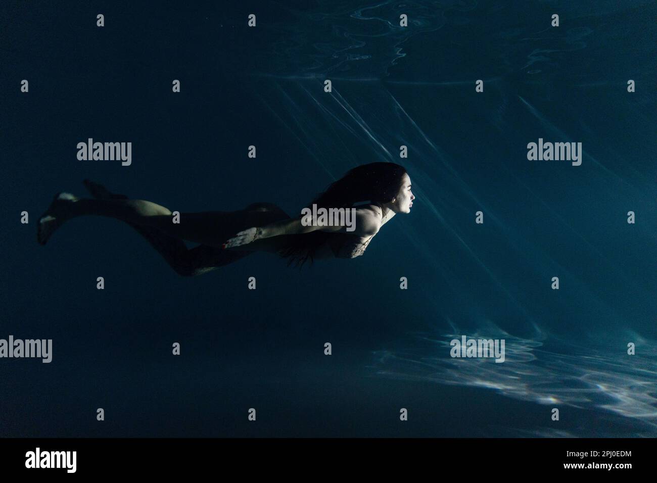 Underwater shoot of beautiful woman with long hair swimming in water in